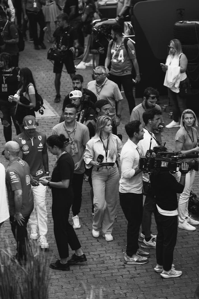 why-choose-us Black and white image of a bustling outdoor event with reporters and camera crews.