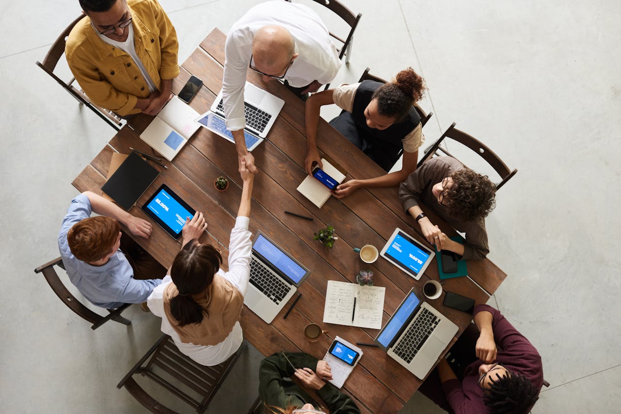 services-02 Top view of a diverse team collaborating in an office setting with laptops and tablets, promoting cooperation.