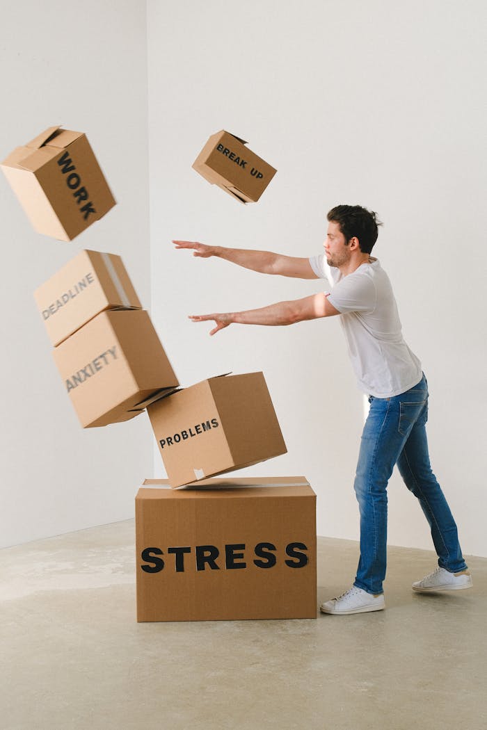 who-we-are Full body of young man in sneakers and jeans pushing and falling boxes saying Work Problems Anxiety Stress and Deadline while fighting with problems